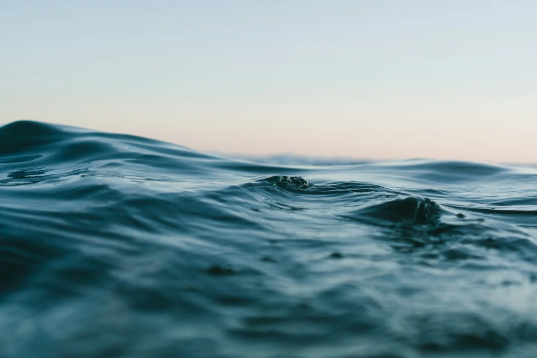Gentle blue ocean waves beneath a pale sky